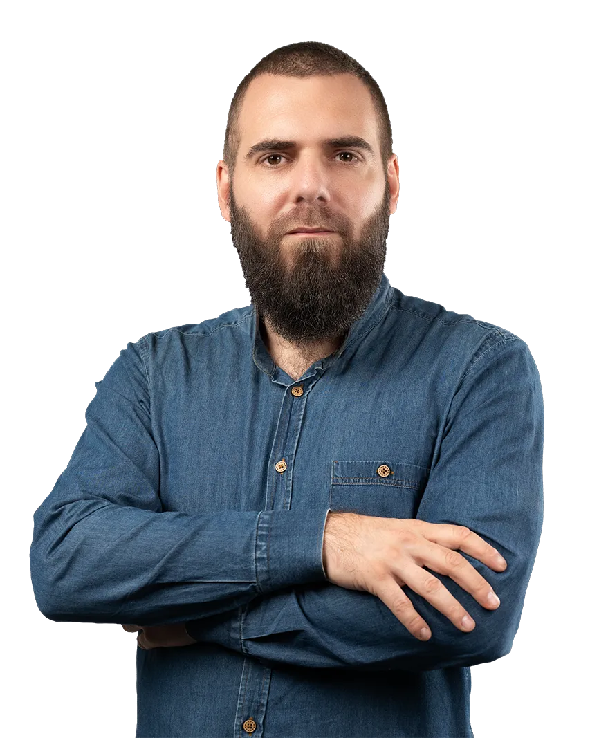 Bearded man in a blue denim shirt with arms crossed, facing forward.