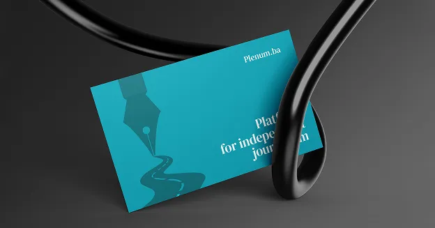 Blue business card with a fountain pen nib graphic and partial text reading 'Platform for independent journalism', held by a black clamp against a dark background.