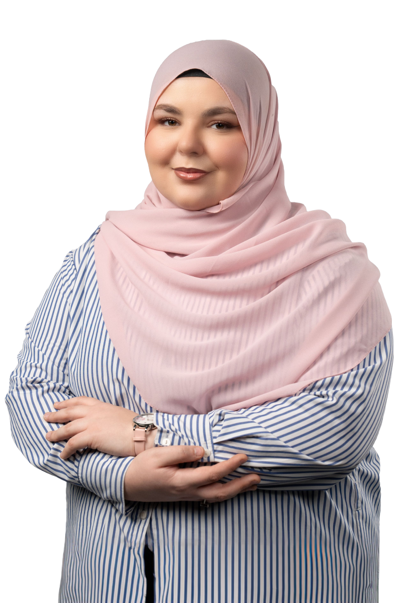 Smiling woman wearing a pink hijab and a blue and white striped shirt with arms crossed.