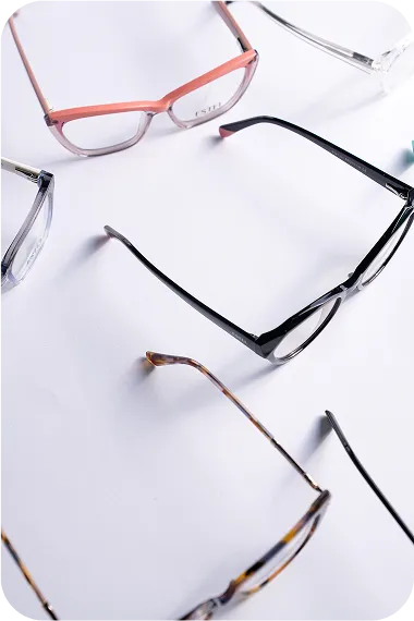 Several pairs of eyeglasses with different frame colors arranged on a white surface.