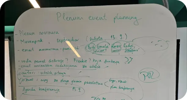 Whiteboard with handwritten notes in green marker outlining 'Plenum event planning' details, including date, location, email, agenda, and panel discussion points.